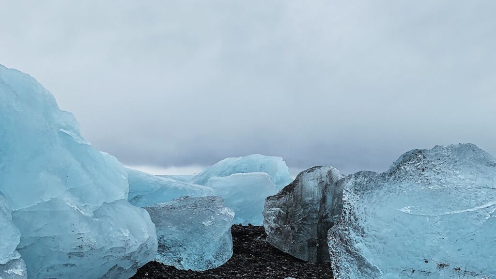 Blocos de gelo azul na praia de areia preta de Jökulsárlón, na Islândia