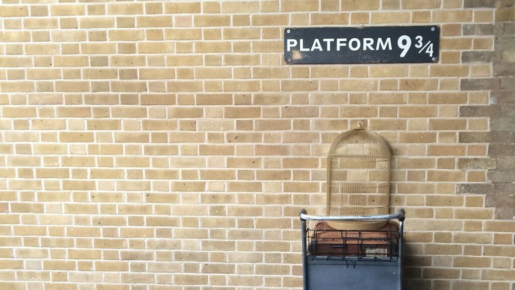 Plataforma 9¾ com carrinho de malas atravessando a parede em King's Cross, Londres